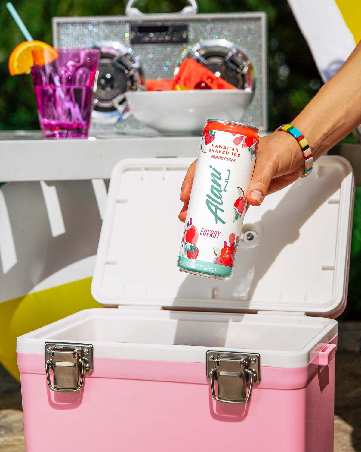 A person holding a can of Energy Drink in Hawaiian Shaved Ice flavor by a pink cooler. 