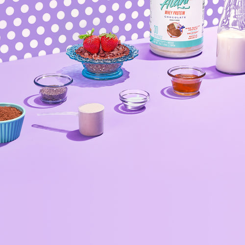 Whey Protein - Chocolate showcasing a variety of food ingredients on a purple table.