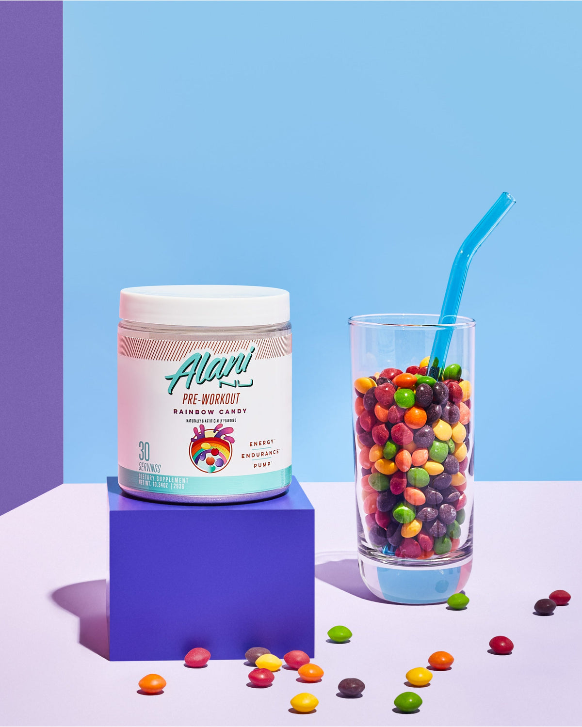 Pre-Workout in Rainbow Candy flavor next to a glass of skitles in glass.