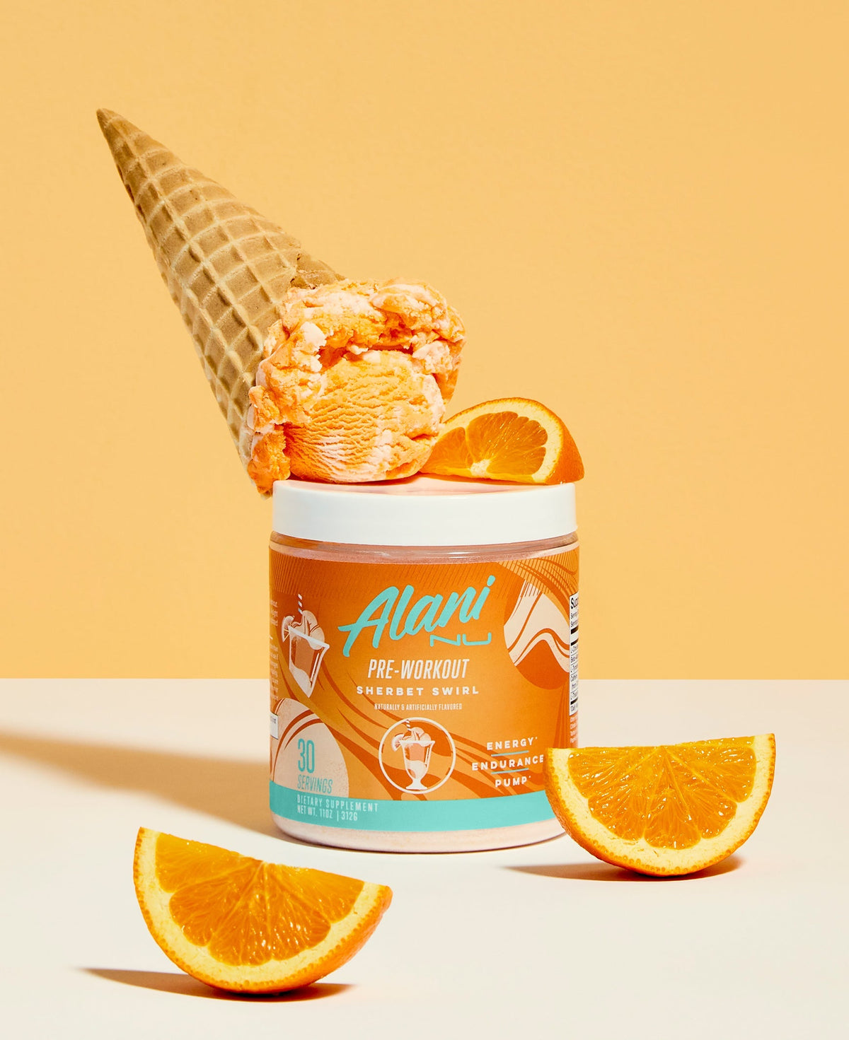 A container of Pre-Workout in Sherbet Swirl flavor next to an ice cream cone and orange slices on top of it.